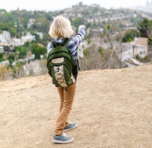 Boy points towards urban landscape while exploring outdoors, signifying adventure and curiosity.