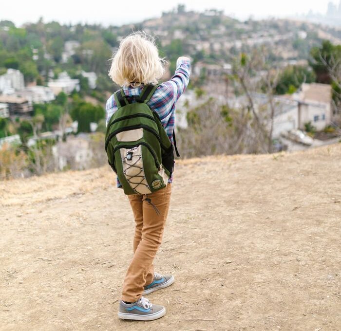 Boy points towards urban landscape while exploring outdoors, signifying adventure and curiosity.
